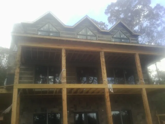 Dormers and porch framing on a large log home under construction — Roof Coating work by our crew in Verden