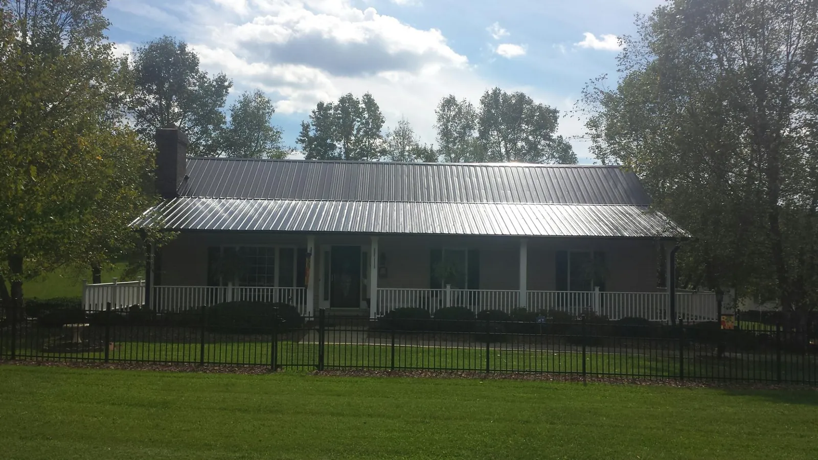 Gray metal roof on a brick ranch with a full width front porch — Gutter Guard Installation work by our crew in Verden