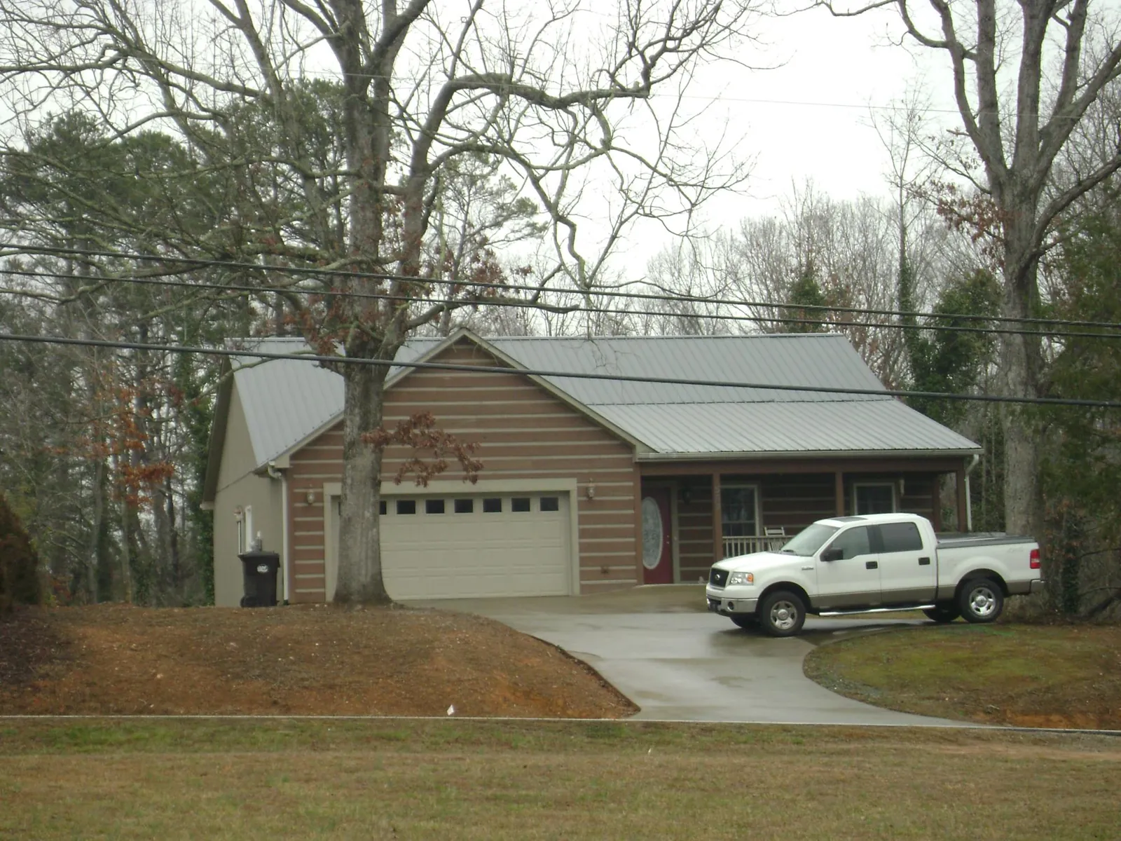 Gray metal roof on a log sided house with an attached two car garage in Verden