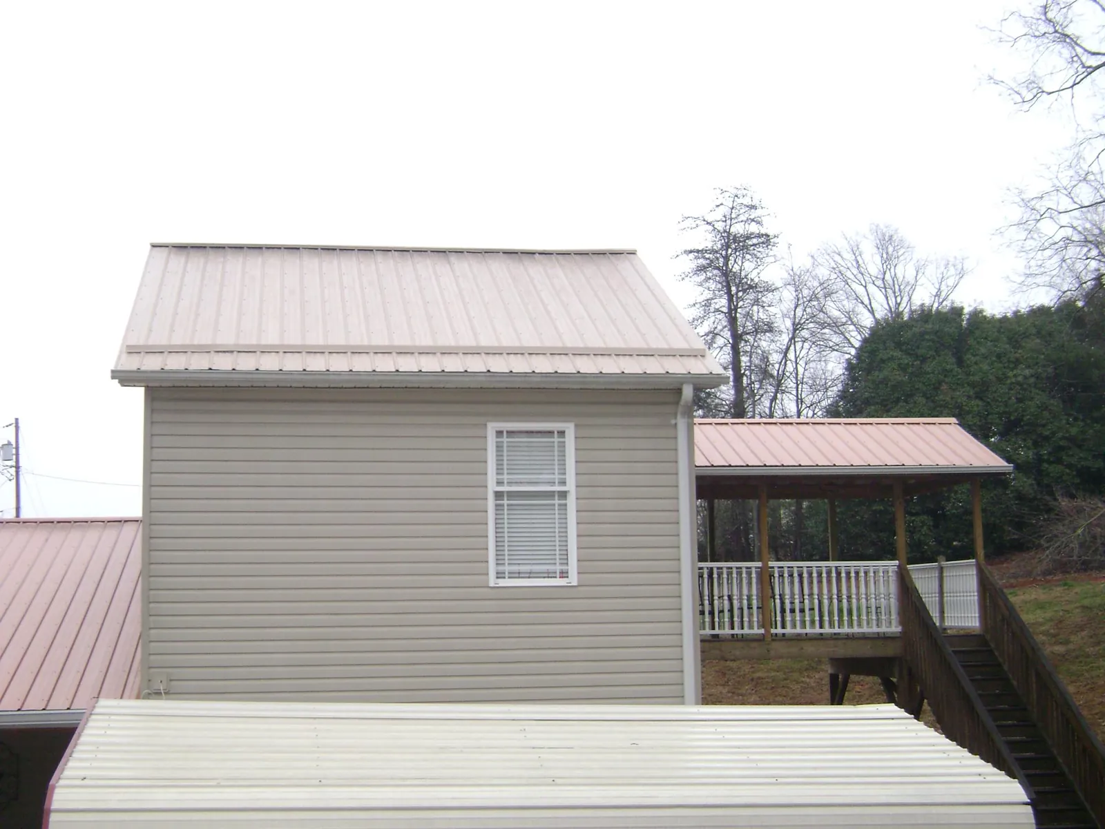 Tan metal roofs on a two story addition and attached porch, from a Roof Replacement job in Verden